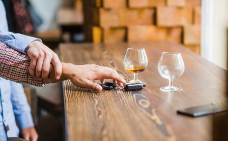 Mężczyzna powstrzymuje przyjaciela przed zabraniem kluczyków samochodowych ze stołu po wypiciu alkoholu