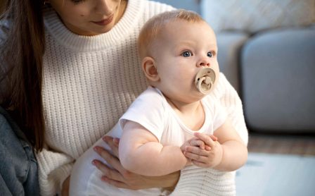 niemowlak ze smoczkiem na rękach mamy